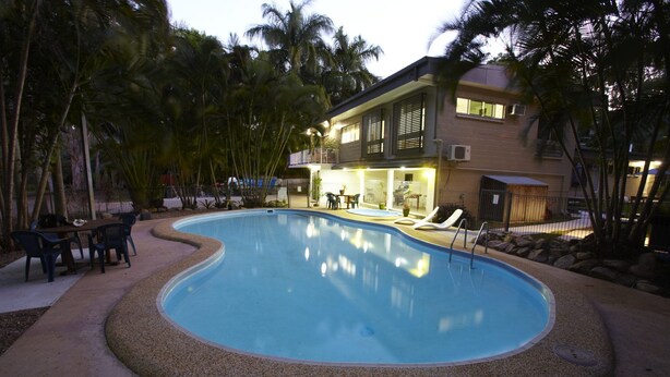 A swimming pool with a pebble edge, surrounded by lounge chairs and a dining area. - BrookeHaven (Arcadia)