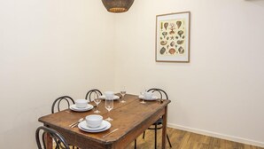 A dining area with a wooden table set for four, white plates, bowls, and wine glasses. - Sail Rock Apartment 1 (Picnic Bay)
