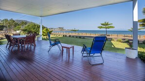 Un espacio al aire libre techado con una terraza de madera, asientos y vista a la playa y al océano.
