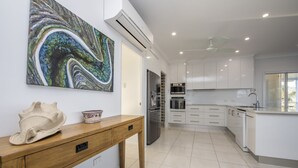 Una cocina moderna con armarios blancos, electrodomésticos de acero inoxidable y una mesa de comedor de madera.