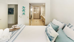 A hotel room with a bed, a bathroom with a shower, and a hallway leading to another room. - Blue on Blue Apartment 815 (Nelly Bay)