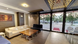 A modern lobby with a sofa, a black armchair, and a wooden coffee table. - Hotel Grandeur (Pune)