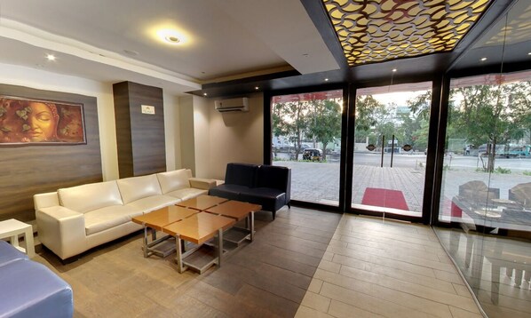 Un lobby moderno con un sofá, un sillón negro y una mesa de centro de madera.