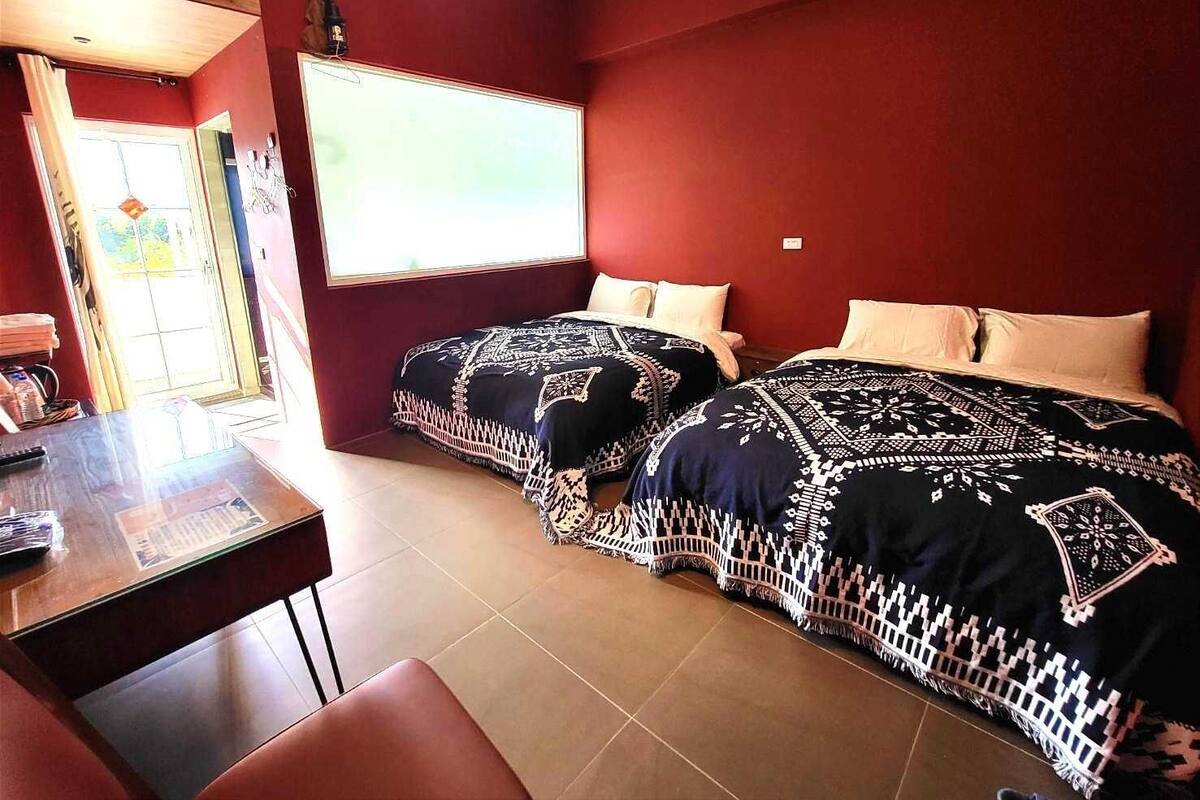 Una habitació amb dos llits, un escriptori i una finestra.