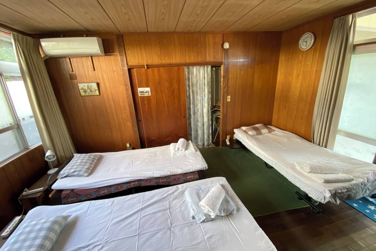 Een kamer met twee bedden, houten wanden, een klok en een raam met gordijnen.