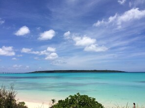 A beach with clear turquoise water, a distant island, and a bridge in the background. - Body Balance House (Miyakojima)