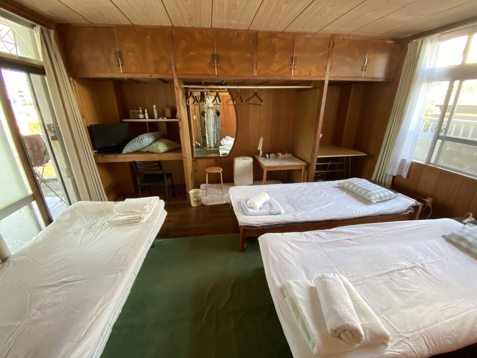 A room with two beds, a desk, a chair, a small table, and a mirror.