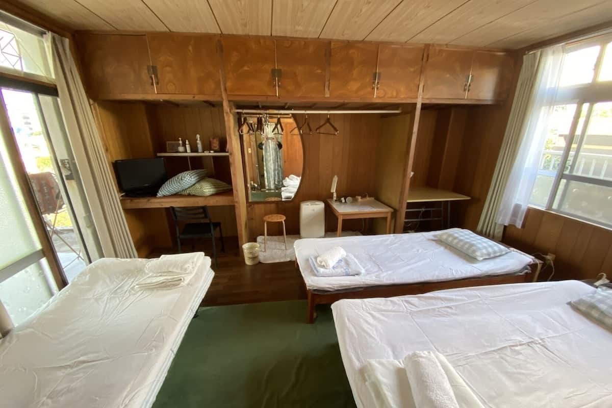 Een kamer met twee bedden, een bureau, een stoel, een klein tafeltje en een spiegel.