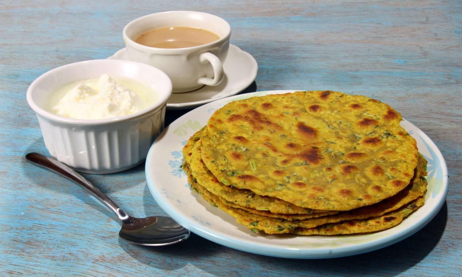 Une assiette de galettes, une tasse de café et un ramequin de beurre.