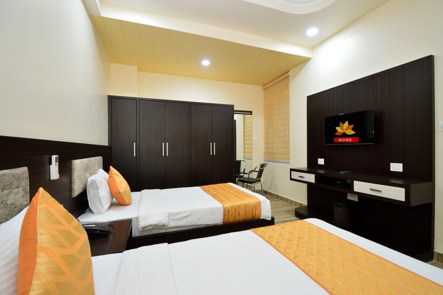 Habitación de hotel con dos camas, televisión, escritorio y armario.