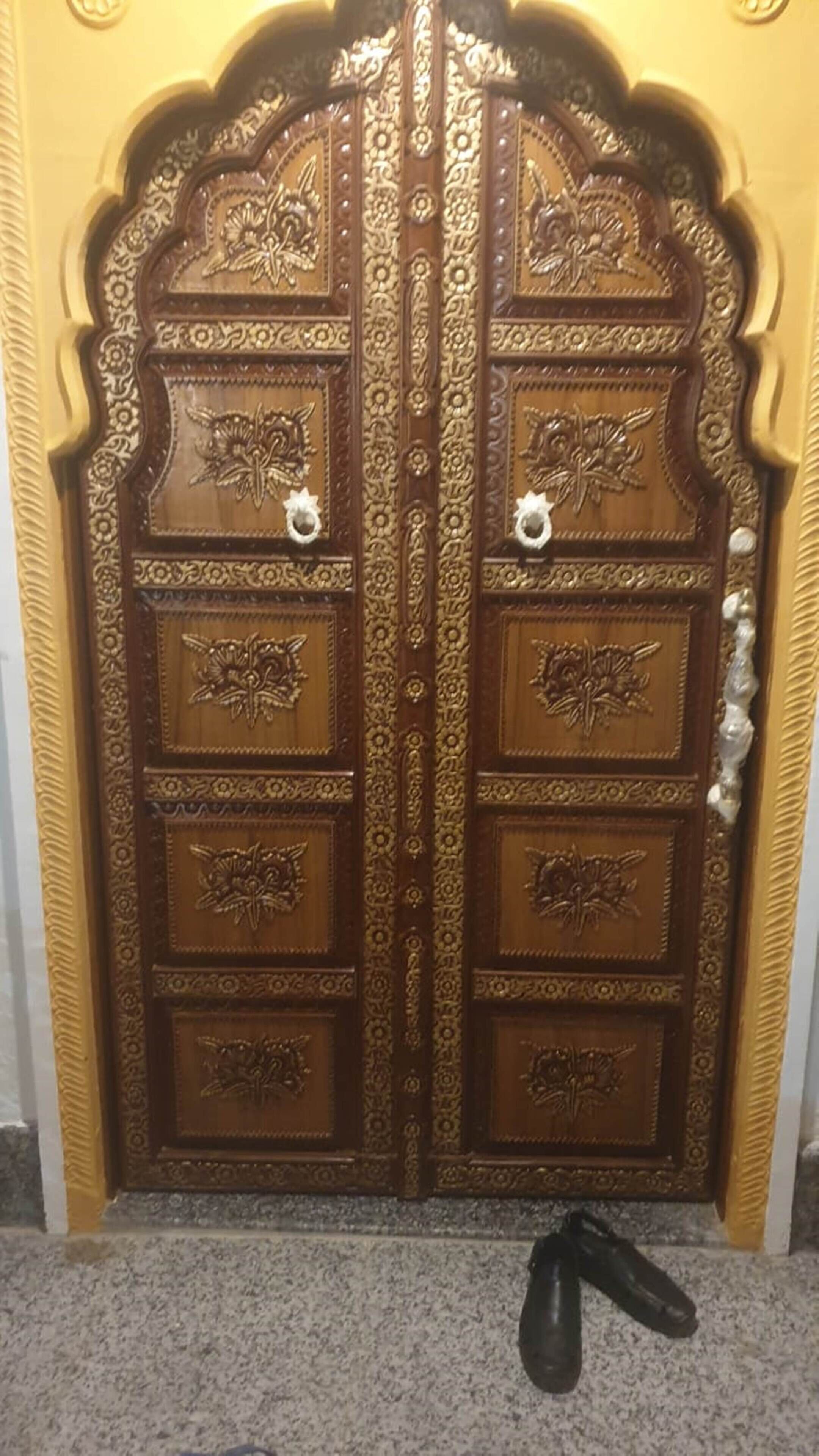 Een houten dubbele deur met ingewikkelde houtsnijwerken en twee ronde deurklinken.