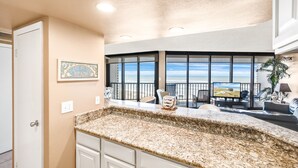 A kitchen with a granite countertop, a dining area with a view, and a living room with a TV.
