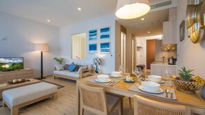 A modern living room with a sofa, dining table, and a TV. - Apartment on the Beach Maikhao Pool View 72sqm (Mai Khao)