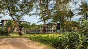 A pathway leading to a building with a sign for 'DAAN MAI KHAO Sales Gallery Open Daily 6am-6pm'. - Apartment on the Beach Maikhao Pool View 72sqm (Mai Khao)