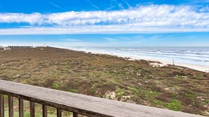 Eine Küstenlandschaft mit einer Holzterrasse mit Blick auf Strand und Meer.