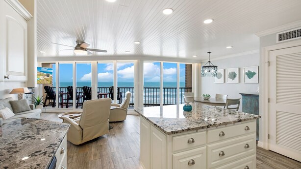 A spacious kitchen with a large island, a ceiling fan, and a view of the ocean through large windows. - Sea Gull #808: Beachfront 2 Bedroom 2 Bath with Spectacular Views and 24 Hour Management (Port Aransas)