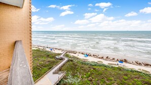 A beach view with a wooden deck and a brick wall. - Sea Gull #808: Beachfront 2 Bedroom 2 Bath with Spectacular Views and 24 Hour Management (Port Aransas)