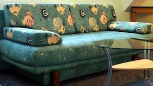 Ein grünes Sofa mit Tiermuster, ein Glastisch und ein Teppichboden.