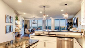Una cocina moderna con una isla grande, electrodomésticos de acero inoxidable e iluminación colgante.