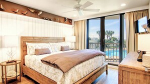 Un dormitorio amplio con una cama de madera, un ventilador de techo y vistas a una piscina.