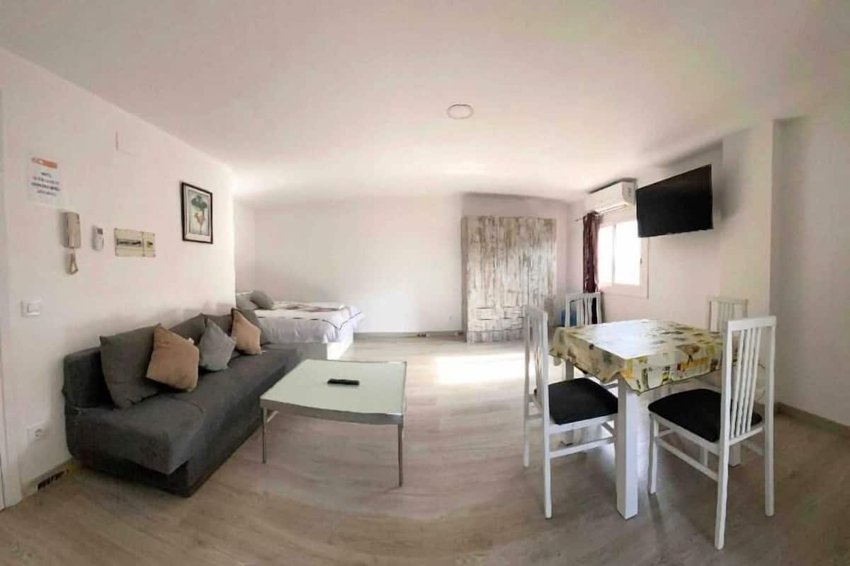Uma sala de estar com sofá, mesa de centro e área de jantar com mesa e cadeiras.