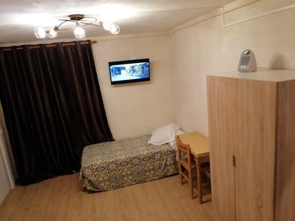 A small room with a bed, a desk, a chair, a television, and a wardrobe. - Hostel Penedes (Vilafranca del Penedes)