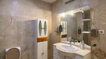 A bathroom with a toilet, vanity with a sink, and a mirror.