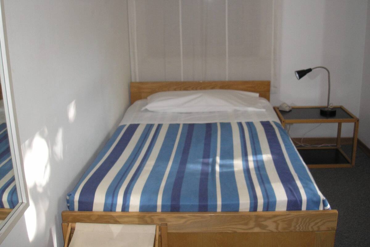 Een slaapkamer met een bed, nachtkastje en bedtafel.