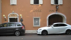 A building with a sign that reads "DOGE INN HOTEL" and a car parked in front.