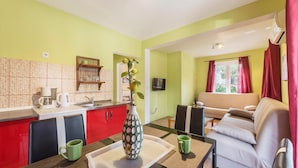 Een ruimtelijk ingerichte leefruimte met een kitchenette, een bank en een televisie.