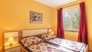 Een slaapkamer met een bed, twee nachtkastjes, een lamp, een schilderij en een raam met gordijnen.