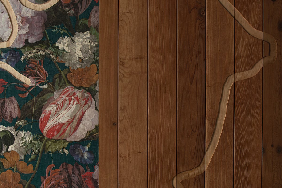 A wooden floor with a floral-patterned wallpaper on the left.