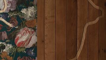 A wooden floor with a floral-patterned wallpaper on the left.