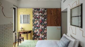A bedroom with a bed, a chair, a small table, and a window.