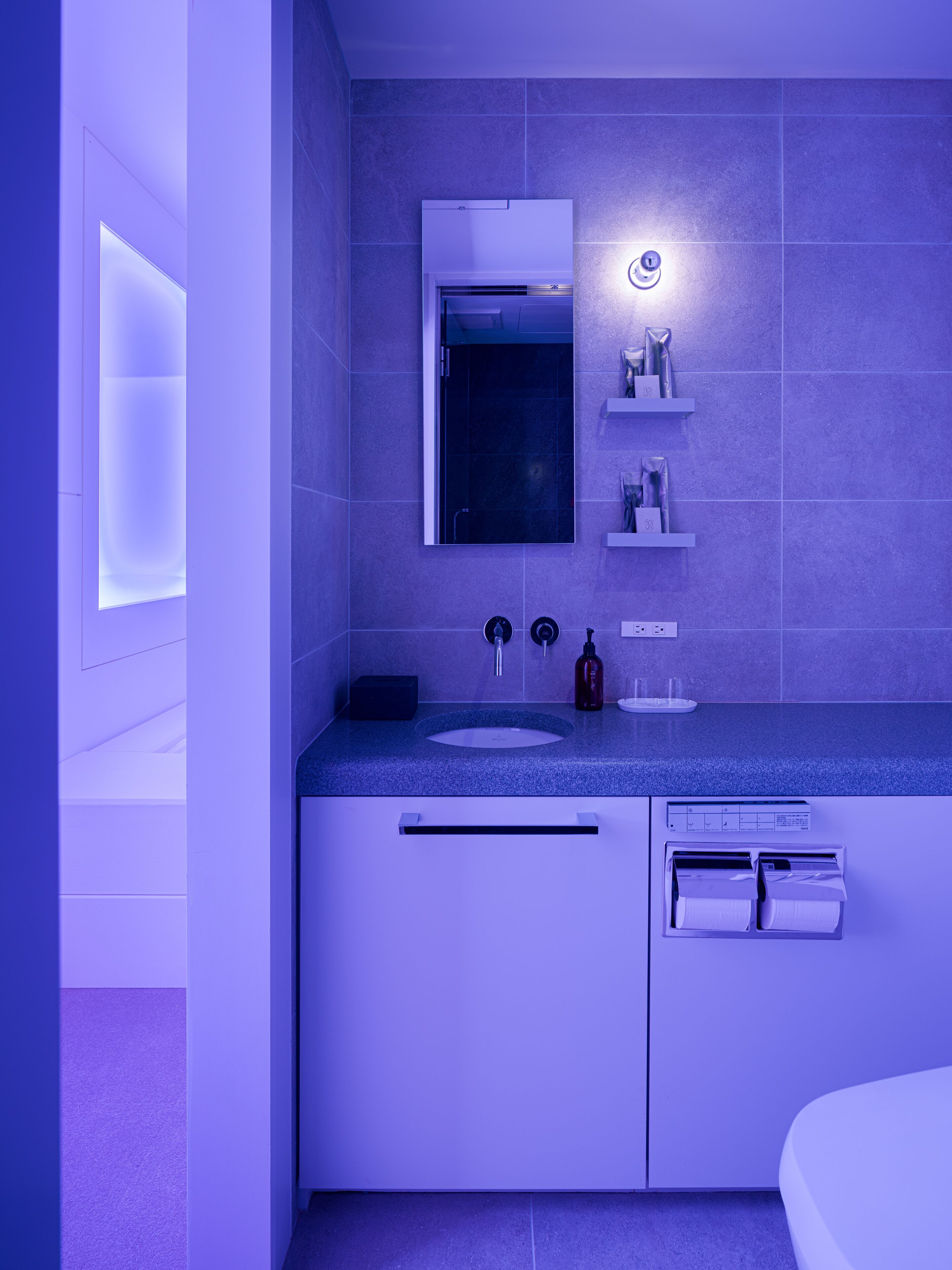 A modern bathroom with a built-in sink, a mirror, and a shower.