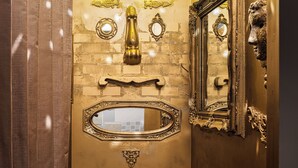 A bathroom with a gold vanity, a mirror, and a light fixture above the sink. - BnA_WALL (Tokyo)