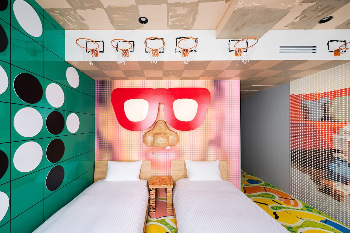 A room with a bed, a wall with circular patterns, and a ceiling with basketball hoops.