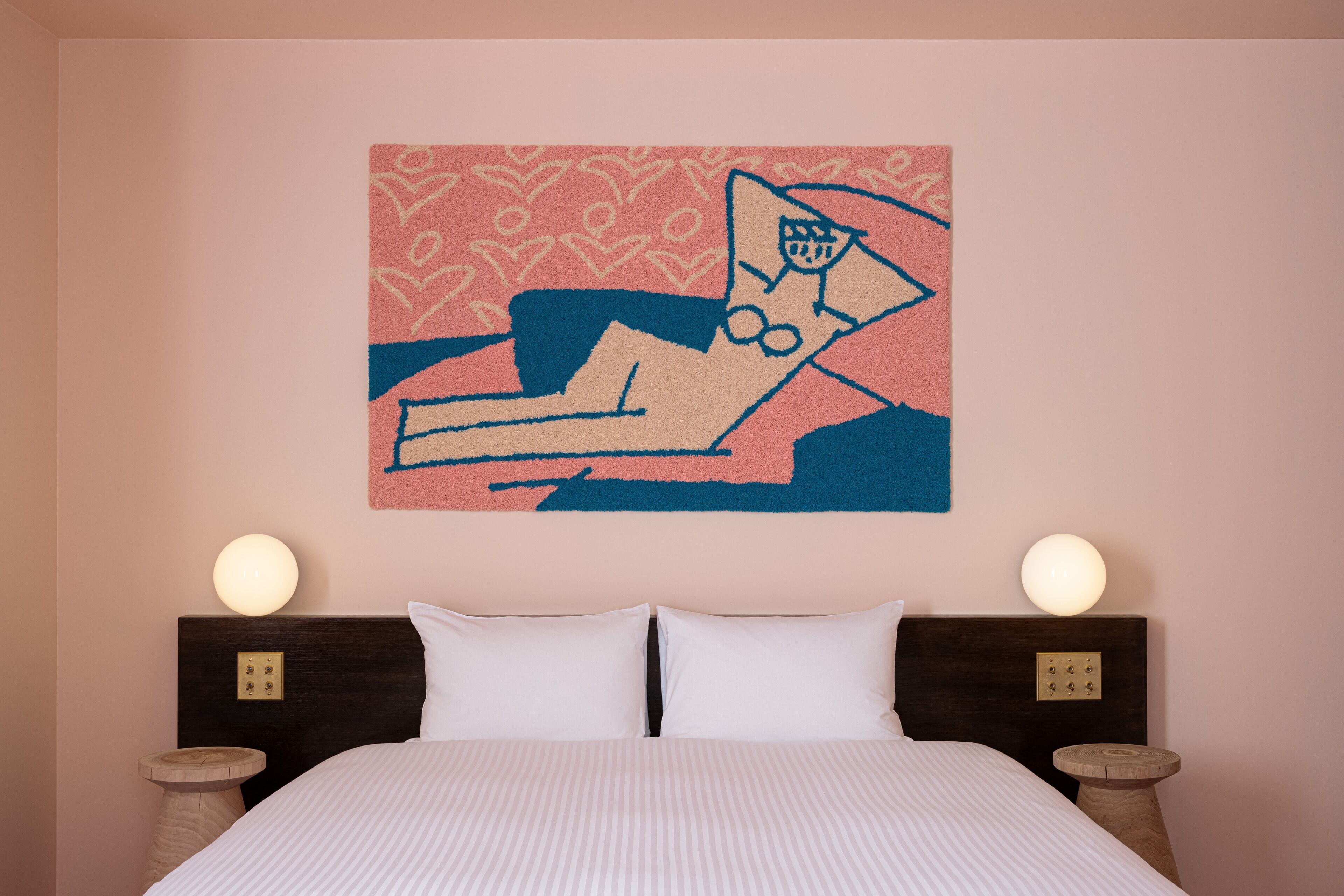 A bedroom with a bed, two bedside tables, and a wall-mounted artwork.
