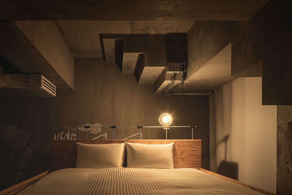 A bedroom with a wooden headboard, a bedside lamp, and a bed with striped bedding.