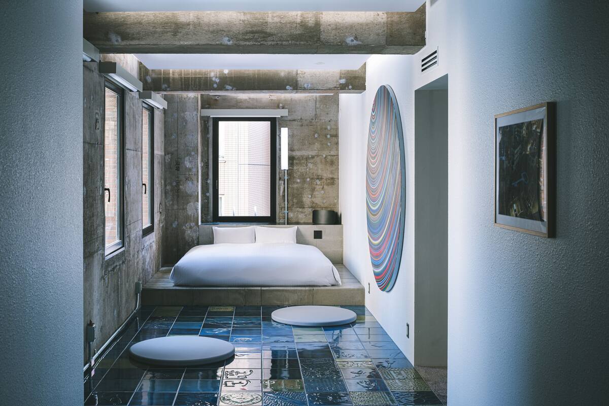 A modern bedroom with a large bed, a window, and a unique tiled floor.