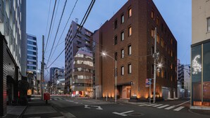 A multi-story building with a modern architectural design, featuring a prominent corner entrance and a visible fire escape. - BnA_WALL (Tokyo)