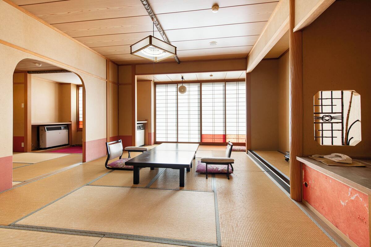 A traditional Japanese room with tatami flooring, a low table, and seating.