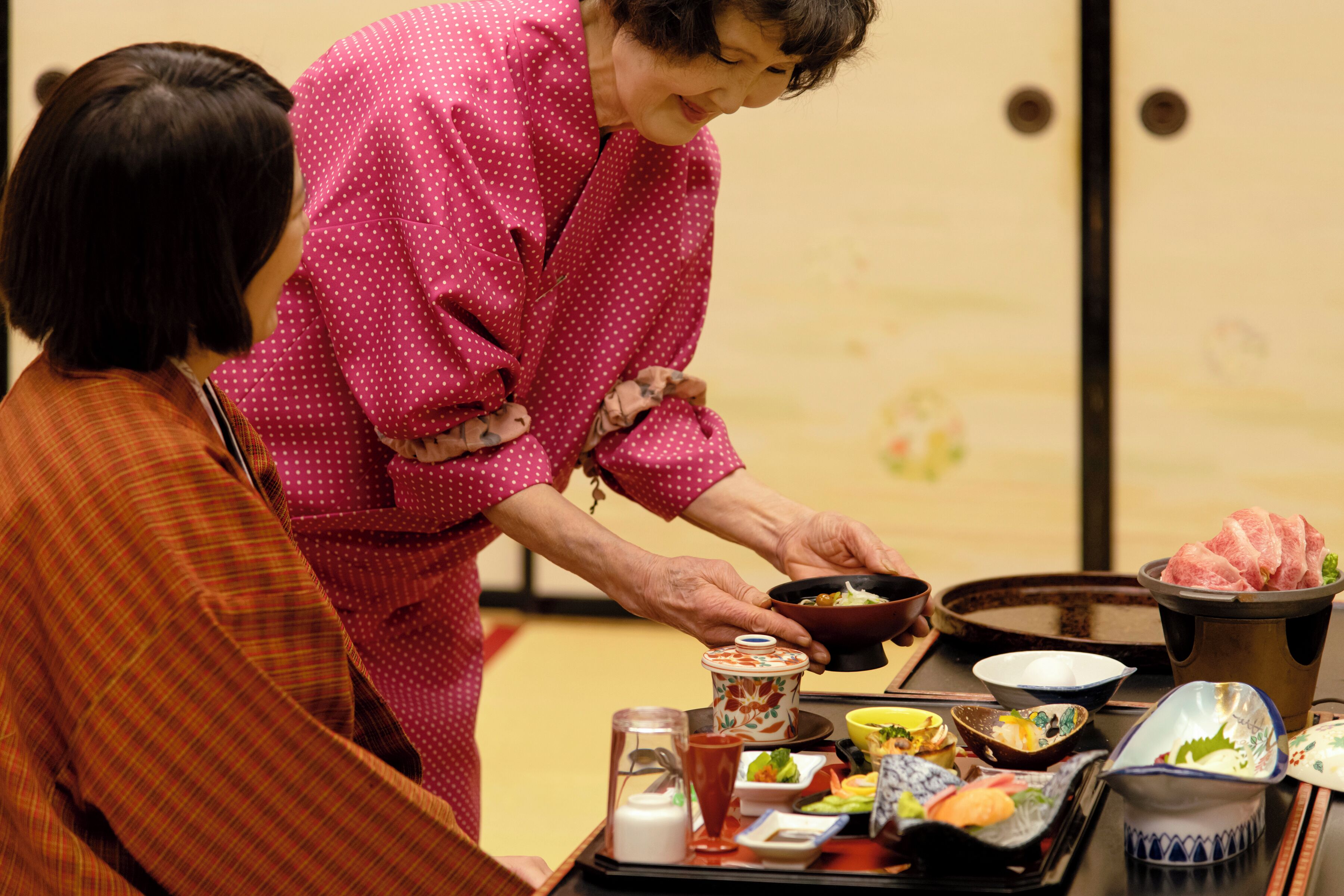 A dining table with various dishes and a person serving food.