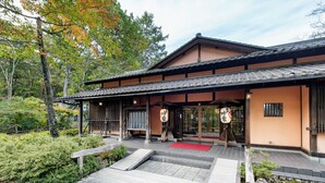 Un bâtiment traditionnel japonais, avec un toit recouvert de tuiles, des poutres en bois et un tapis rouge à l’entrée.