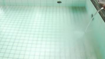 Une piscine dont le fond est recouvert d’un motif quadrillé et qui comporte une fontaine ou un autre élément décoratif aquatique sur le côté droit.