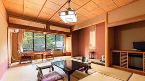 Une pièce de style japonais traditionnel, avec un sol recouvert de tatamis, une table basse et un téléviseur.
