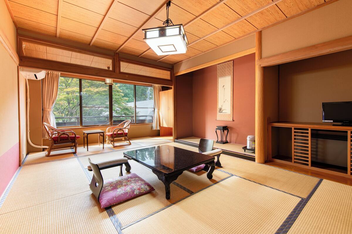 A traditional Japanese room with tatami flooring, a low table, and a television.