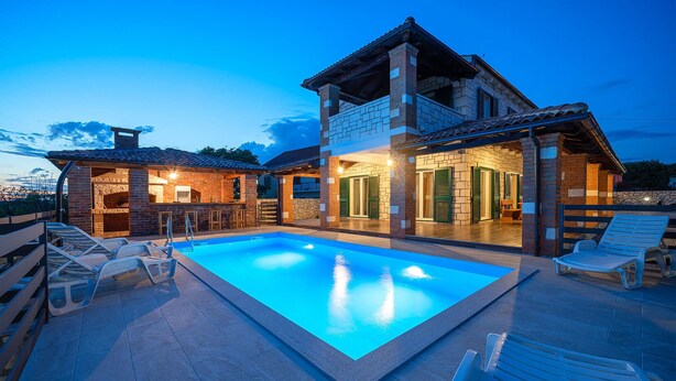 Una casa de dos pisos con piscina, mobiliario de exterior y zona de barbacoa.
