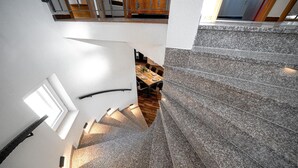 Una escalera de piedra que sube a un comedor con una mesa y sillas de madera.