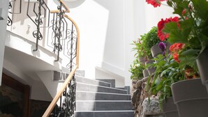 A staircase with a wooden handrail, stone wall, and potted plants. - Step One - Luxury Suites right in the heart of Acropolis next to metro station (Athens)
